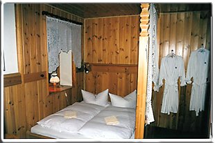 Zimmer mit Holzbetten und weißen Gardinen